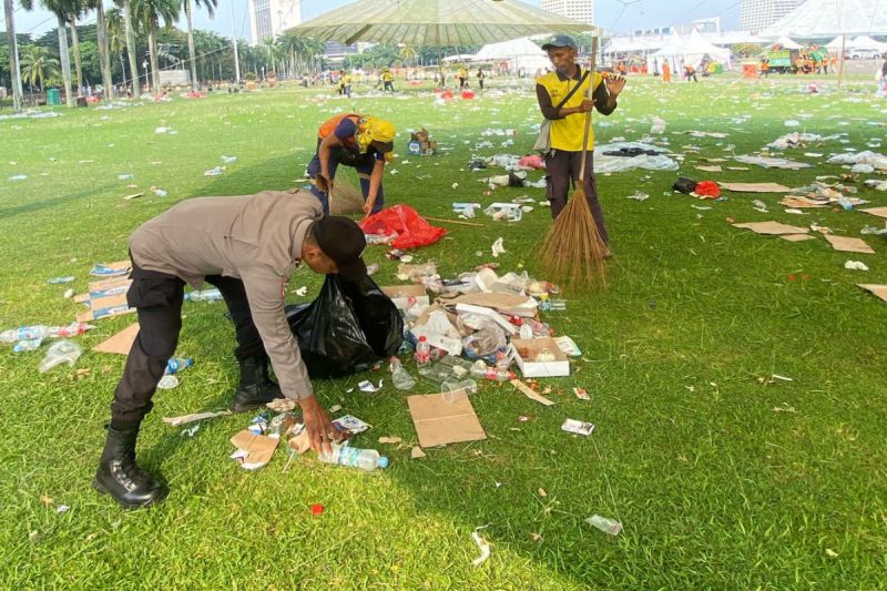Polisi ikut bersihkan sampah usai peringatan Hari Buruh di Monas