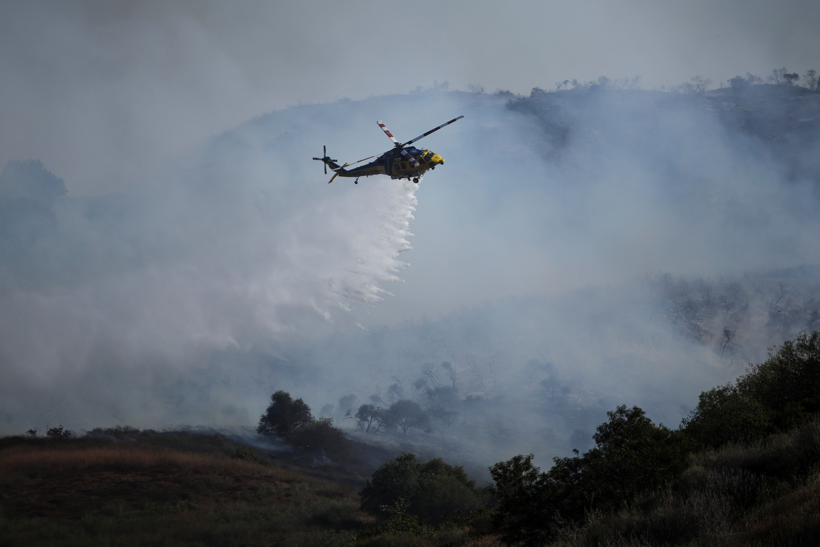 Helikopter memancarkan api yang mengancam rumah-rumah di lereng bukit di California